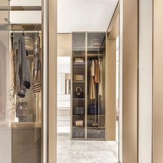 an open closet with clothes hanging on the wall and other items displayed in glass doors