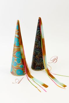 two party hats with streamers on the top one is blue and orange, while the other has gold