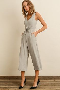 Cropped jumpsuit featuring a plunging v-neckline, wrap-back/tie-front bodice, and a cutout detail at the back Hidden back zipper. Model is 5'8'' and wearing size small Gray Fitted V-neck Jumpsuits And Rompers, Spring Solid Color Jumpsuits And Rompers With Tie Back, Spring Jumpsuits And Rompers With Tie Back, Spring Tie Back Jumpsuits And Rompers, V-neck Tie Back Jumpsuit For Party, V-neck Party Jumpsuit With Tie Back, V-neck Jumpsuit With Tie Back For Party, Chic Jumpsuits And Rompers With Tie Back, Chic Sleeveless Jumpsuits And Rompers With Back Zipper