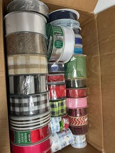 a cardboard box filled with lots of different types of ribbons and tape on top of each other