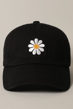 a black hat with a white daisy embroidered on the front and yellow center in the middle