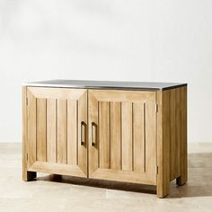 a wooden cabinet sitting on top of a floor next to a white wall with black trim