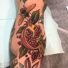 a person with a tattoo on their arm has a pomegranate in the shape of a heart