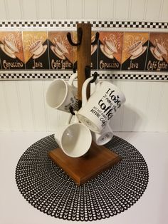 four coffee mugs are stacked on a wooden stand with black and white designs around it