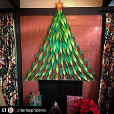 a christmas tree made out of green paper on top of a fireplace mantel with presents under it