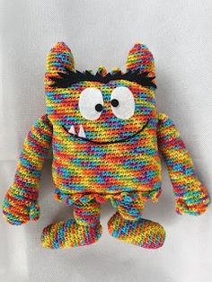 a multicolored knitted stuffed animal with big eyes and an ugly expression on its face