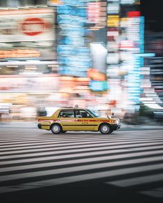 a taxi cab driving down a street next to tall buildings