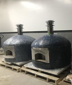 two large round ovens sitting on top of pallets