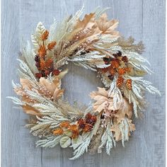 a wreath made out of dried leaves and pine cones on a wooden background with the words fall written below it