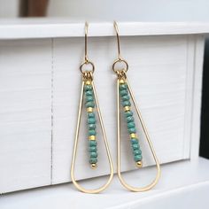 Adorn yourself with opulence and grace with the captivating Harley earrings. Made from gleaming gold, these long teardrop earrings are adorned with delicate turquoise seed beads, adding a touch of exotic charm to your look. Elevate any outfit with these luxurious and alluring earrings. Approximately 2.25” long Made with 14k Gold Filled Turquoise Seed Beads Polished to a high shine Handmade in Montana Sent in a ribboned gift box with polishing cloth Turquoise Wire Wrapped Beaded Earrings, Turquoise Faceted Bead Earrings, Elegant Turquoise Beaded Earrings Nickel-free, Turquoise 14k Gold-filled Earrings With Ear Wire, Bohemian Turquoise 14k Gold-filled Earrings, African Turquoise, Jewelry Packaging, Christmas Shopping, Teardrop Earrings