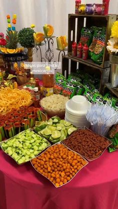 an assortment of food is displayed on a pink table cloth at a party or event