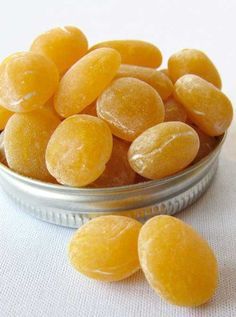 a tin filled with yellow candies on top of a white cloth covered tablecloth