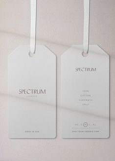 two white tags hanging on a wall with the words spectrum printed on them