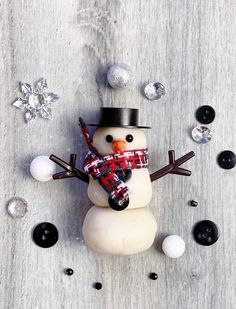 a snowman with a scarf and hat on it's head is standing in front of some balls