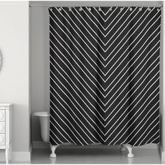 a black and white shower curtain next to a toilet in a room with a mirror