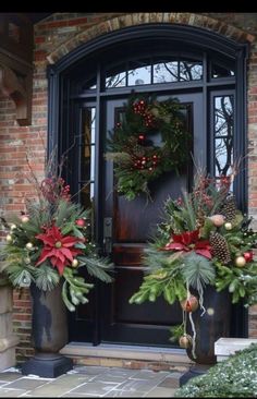 two christmas wreaths on the front door of a house