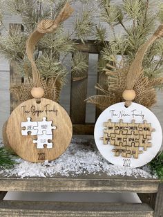 two wooden puzzle pieces sitting on top of snow covered ground next to evergreen branches and pine cones