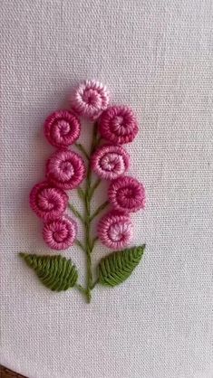 some pink flowers are on a white piece of fabric with green leaves in the middle