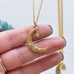 Looking for a celestial necklace with lots of magic and luck? This necklace is it! This necklace is made from a crescent moon charm. The moon charm has three stars with clear cz centers on the front. On the front of the moon the words; magic, luck and love can be seen along with a peace sign and an evil eye. A star drop hangs from the moon. The star like the others has a clear cz crystal in the center. The pendant is gold plated and has a shiny surface. The necklace is finished off with a stainl Celestial Crescent Moon Phase Necklace, Spiritual Crescent Moon Phase Charm Necklace, Spiritual Crescent Moon Phase Necklaces, Mystical Moon-shaped Gold Necklace, Spiritual Crescent Moon Phase Necklace, Celestial Style Star Charm Pendant Necklace, Celestial Moon Charm Necklace For Jewelry Making, Spiritual Crescent Moon Charm Necklaces, Gold Mystical Necklace With Sun And Moon Design