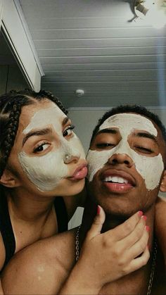 two people with facial masks on and one is kissing the other's cheek as they pose for a selfie