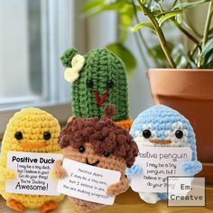 three crocheted stuffed animals sitting next to each other on a table with a plant in the background