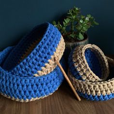 two crocheted baskets and a wooden stick on a table next to a potted plant