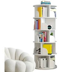 a white book shelf sitting next to a chair in front of a bookshelf