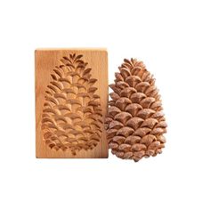 two pine cones are next to each other on a white background, one is carved from wood