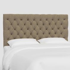 an upholstered headboard with white sheets and pillows