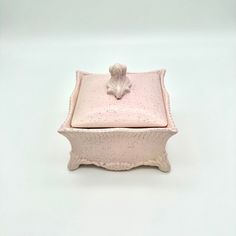 a small pink box with a flower on the lid and a leaf decoration at the top