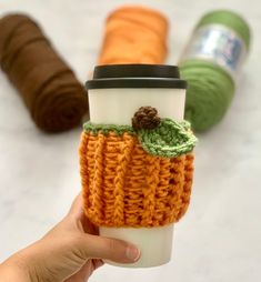 a hand holding a coffee cup cozying with crochet