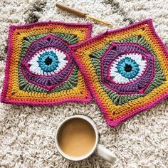 two crocheted coasters with eyeballs on them and a cup of coffee