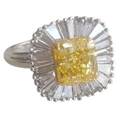 This understated, elegant and enticing ring created by Moguldiam Inc in 18 k white gold features a GIA certified natural fancy vivid yellow Radiant weighing 2.02 carat with VS2 clarity with a halo of tapered baguette accent diamonds weighing 1.10 carat with GH color and VS clarity. The ring size is 7 and is sizable as per requirement. The gold weight is 4.42 grams. Luxury 14k White Gold Diamond Ring With Baguette Diamonds, Yellow Diamond Cut Platinum Ring, Fine Jewelry Yellow Diamond Platinum Ring, Formal Cluster Ring With Baguette Diamonds, Yellow Platinum Diamond Ring Fine Jewelry, Yellow Platinum Diamond Ring With Diamond Cut, Yellow Platinum Diamond Ring, Elegant Yellow Emerald-cut Diamond Ring, Elegant Yellow Emerald Cut Diamond Ring