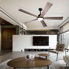 a living room with a ceiling fan and two chairs in front of a flat screen tv