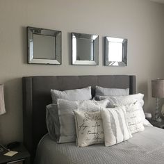 a bedroom with three mirrors above the headboard and pillows on the bed in front of it