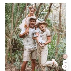 two adults and one child posing for a photo in the woods