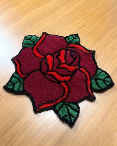 a red rose on a wooden table with green leaves in the center and two petals at the bottom