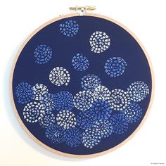 a blue and white circular artwork with circles on the inside, in front of a white wall