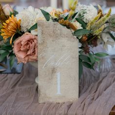 a table with flowers and a sign on it that says calelli 1 in front of the table