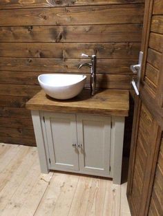 a white sink sitting on top of a wooden counter next to a wall mounted faucet