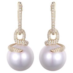 These stunning earrings feature exceptionally large South Sea pearls, their impressive size of 13.5 x 16mm showcasing the pearls' luxurious sheen and near-perfect form. Cradled in the embrace of 14K yellow gold, these magnificent pearls radiate with a soft, opulent luster. Each pearl is adorned with a pavé of glittering diamonds that loop around and ascend in a line of continuous sparkle, totaling 1.18 carats for the pair. These diamonds are meticulously set to complement the pearls with their fiery brilliance, making these earrings a statement of true elegance. Crafted for connoisseurs of fine jewelry, these earrings are a testament to timeless design and the allure of natural beauty, perfect for sophisticated evening events or as the highlight of a bridal ensemble. 14K Yellow Gold South Pearl Diamond Dangle Earrings, Diamond Dangle Earrings, The Embrace, Diamond Glitter, South Seas, South Sea Pearls, Sea Pearls, Pearl Diamond, Stunning Earrings