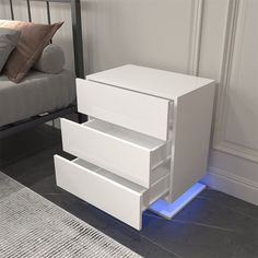 a white night stand with two drawers and a blue light on the bottom drawer, in a bedroom