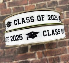 two white graduation ribbons hanging from a brick wall with the words class of 2020 printed on them