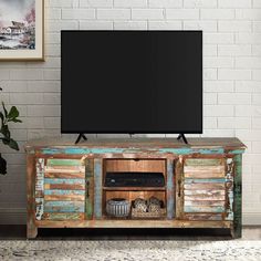 a television stand with an old wooden cabinet and black screen mounted on the wall behind it