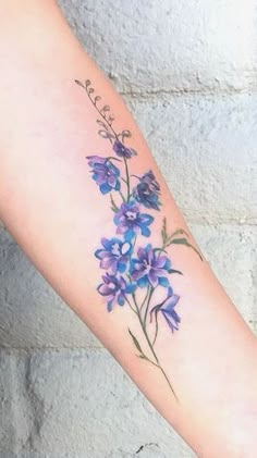 a woman's arm with purple flowers on it and the word love written in cursive writing