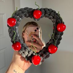 a woman taking a selfie in front of a mirror with cherries on it