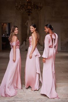 three beautiful women in pink dresses standing next to each other