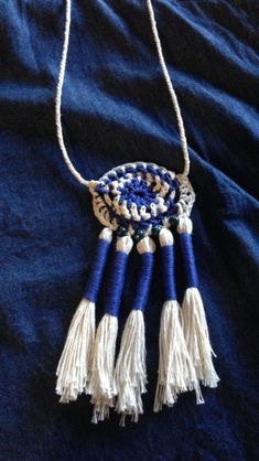 a blue and white necklace with tassels hanging from it's side on a black cloth