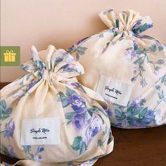 two bags with purple flowers on them sitting on a table