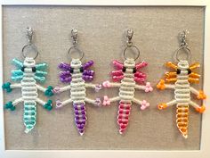 four different colored crocheted seahorses hanging from hooks in a white frame